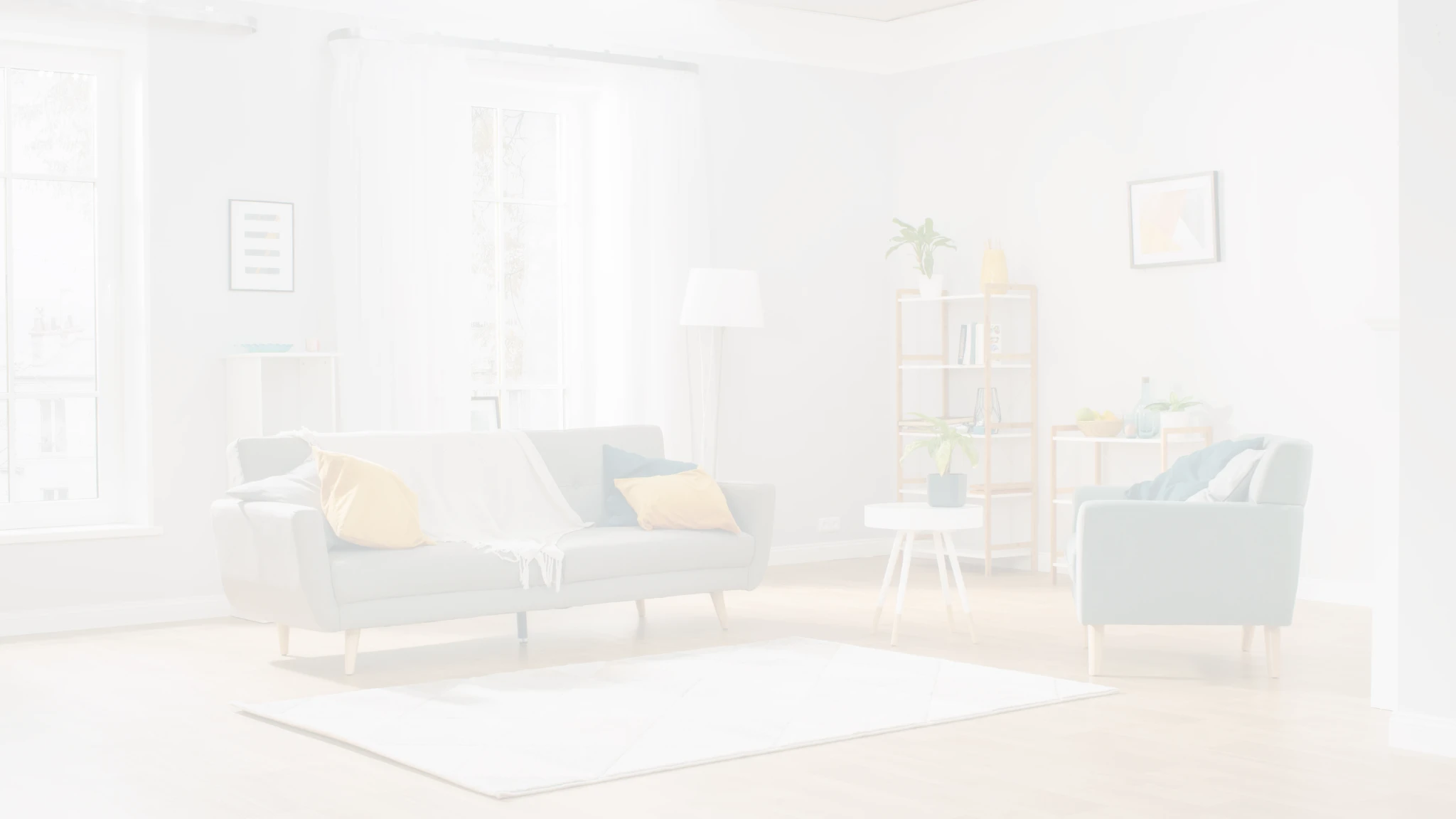 A softly lit living room with a pale sofa, cushions and a large rug.