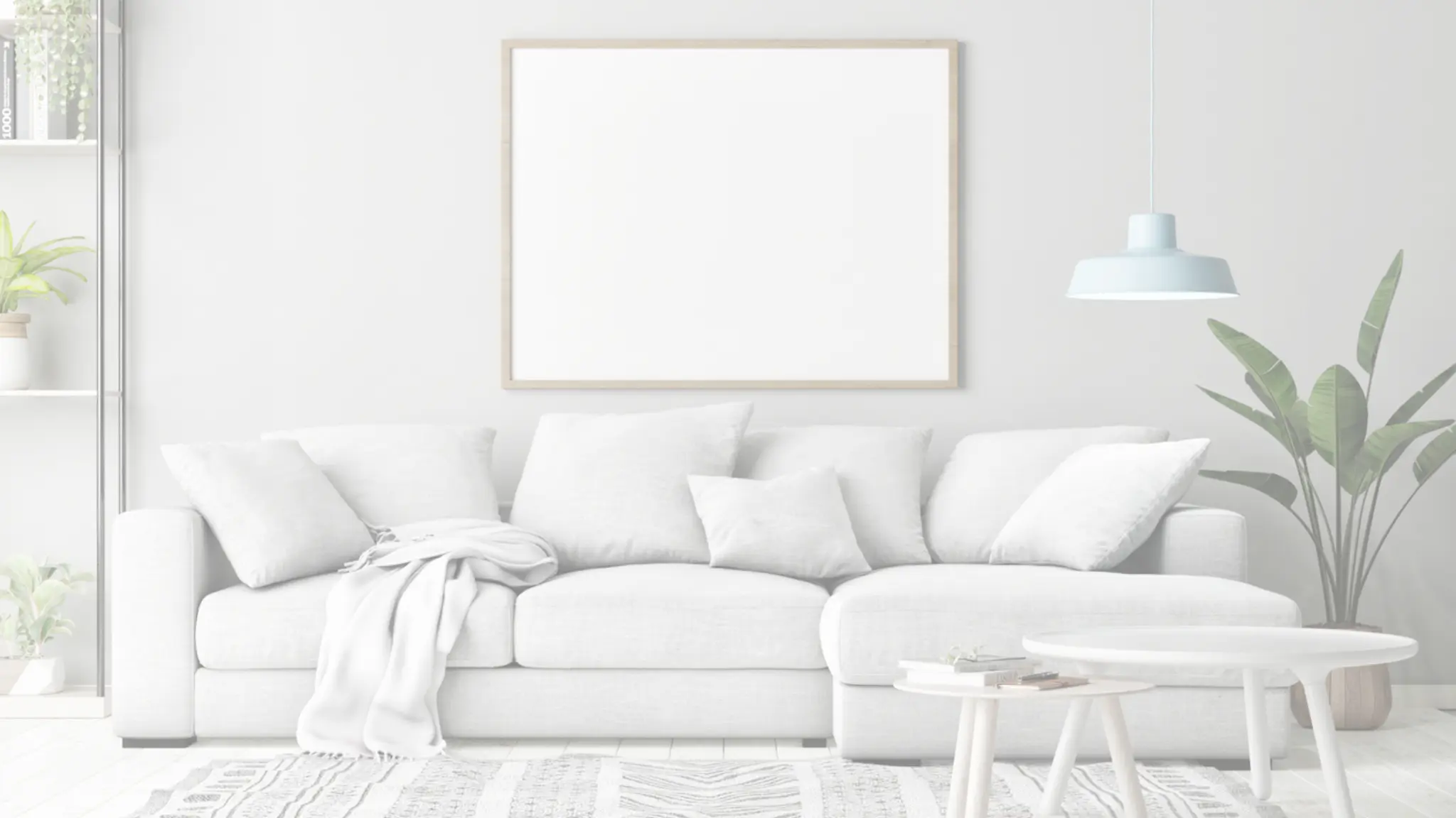 A bright white living room with a pale sofa, a large empty picture frame on the wall and a pendant lamp.